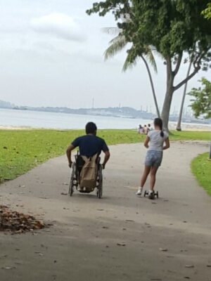 paraplegic father wheels down a path next to his daughter