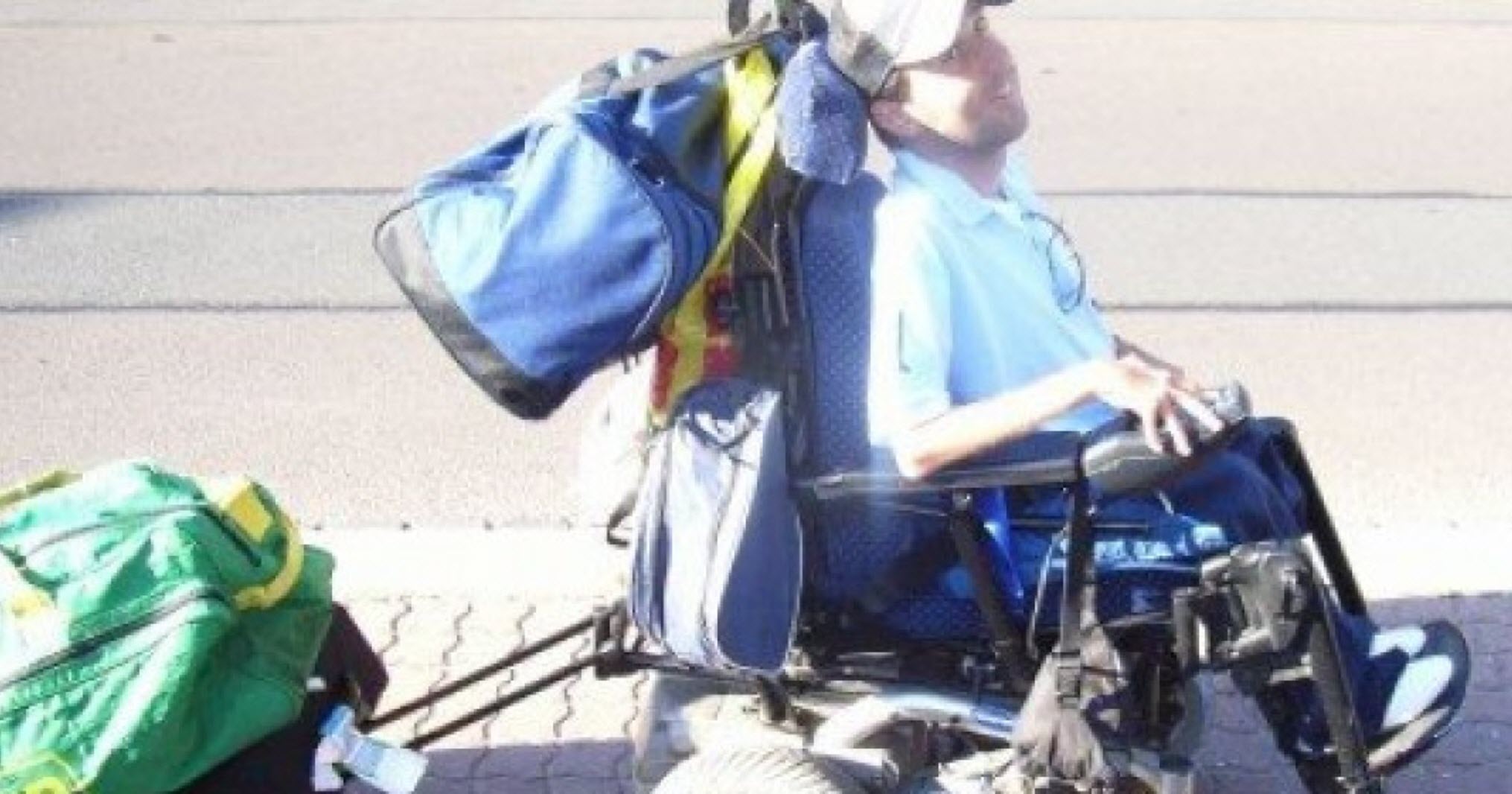 man with sma pulls a suitcase with his wheelchair