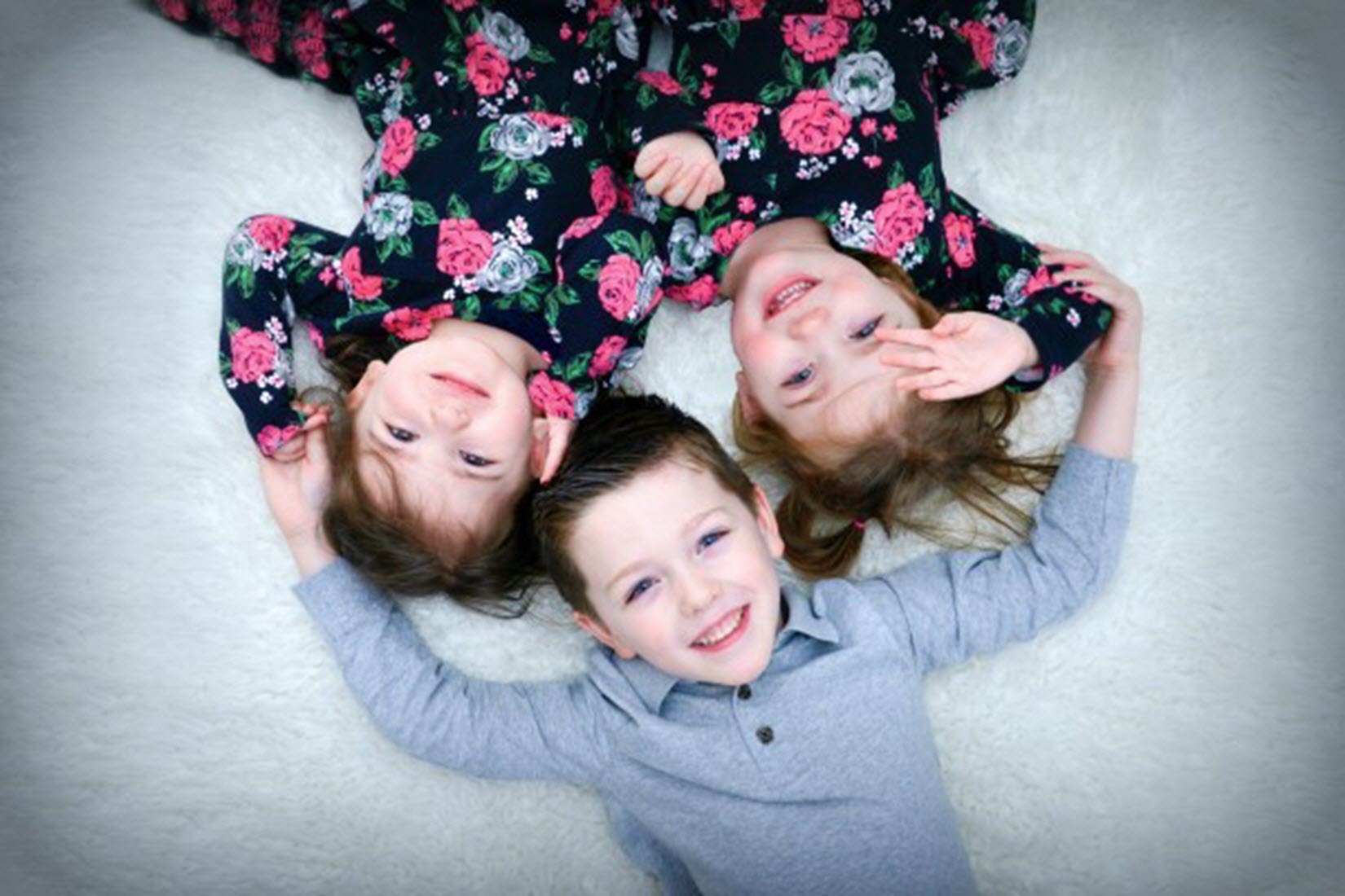 a brother and two sisters smile at the camera
