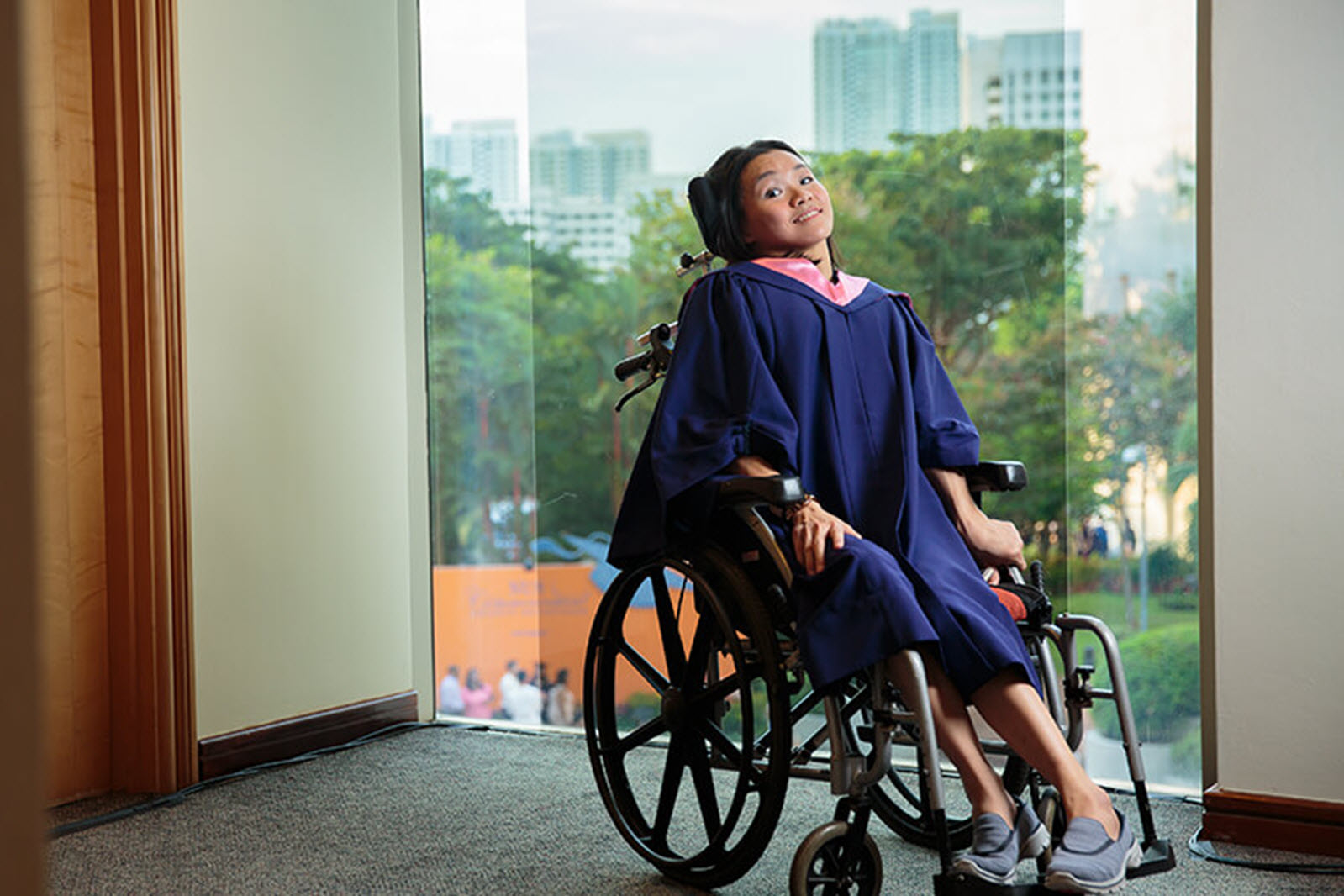 woman in a wheelchair poses in front of a window