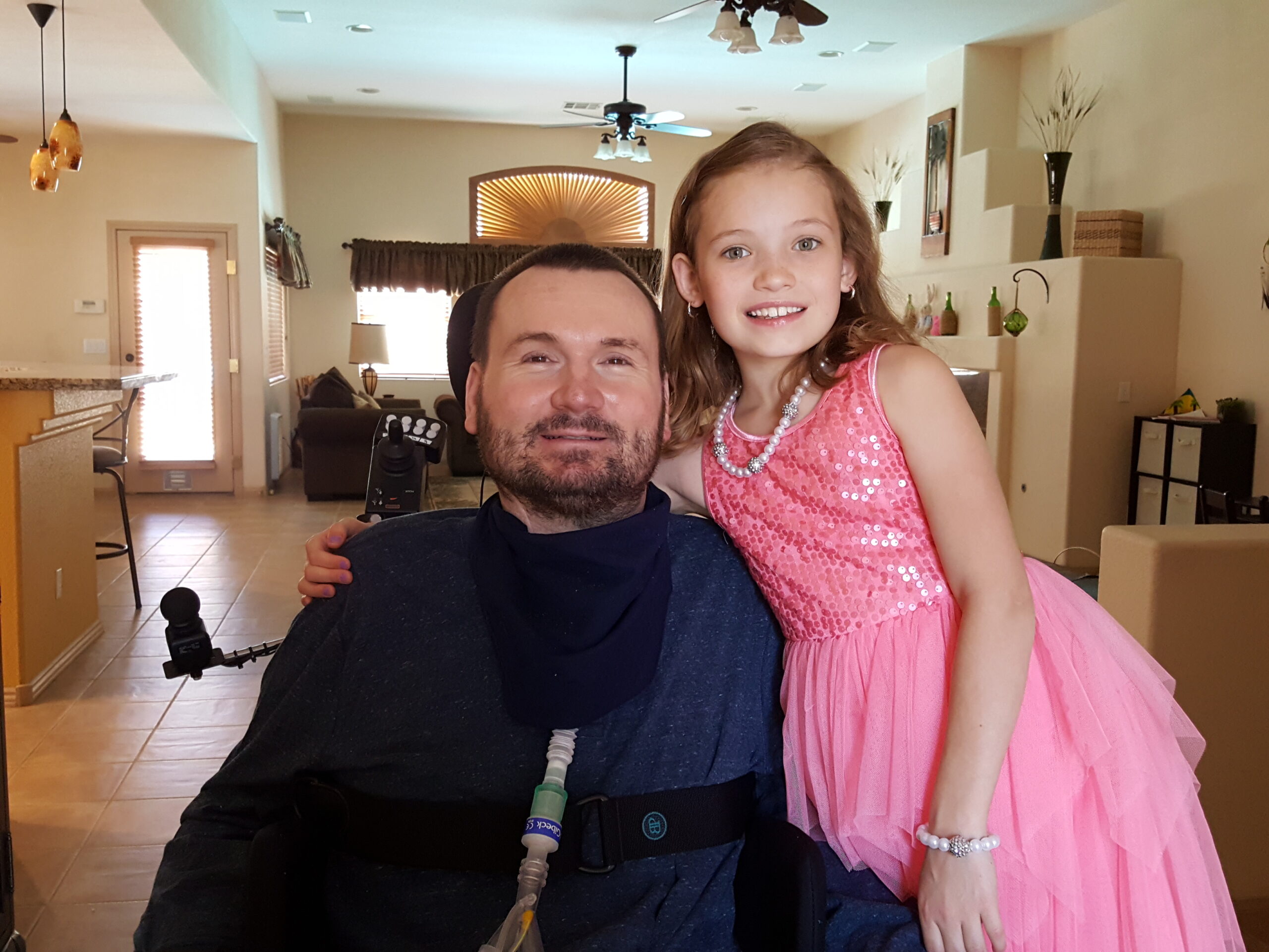 a quadriplegic and his daughter smile