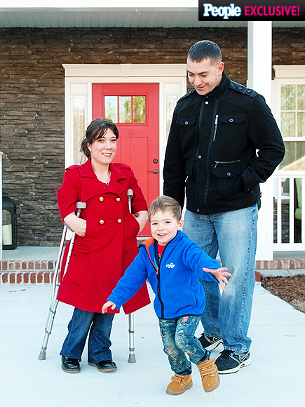 mom with dwarfism stands outside with her husband and son