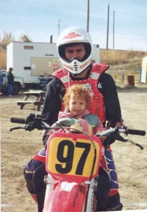 motocross racer and his daughter sit on a motorbike