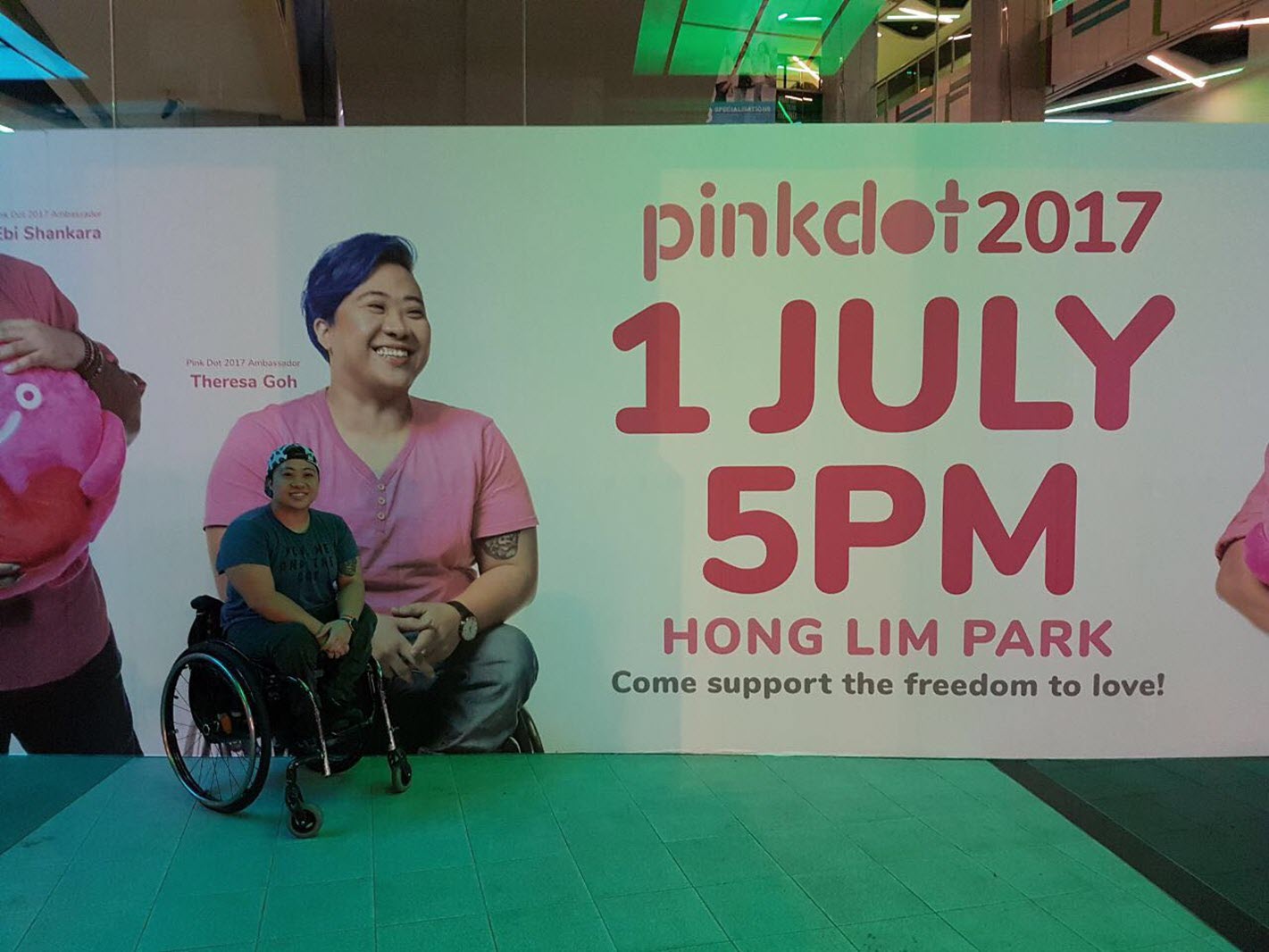 a paraplegic woman poses in front of a banner with her picture on it