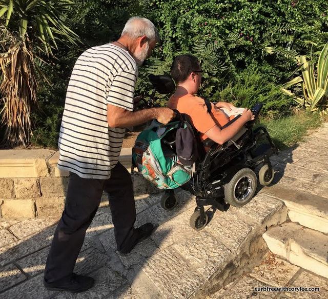 a man pushes a wheelchair user up a ramp in Tel Aviv