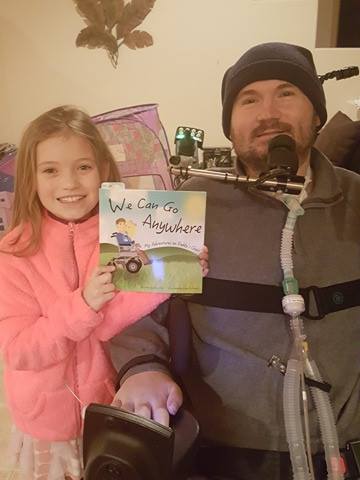 quadriplegic man and his daughter hold up the book We Can Go Anywhere