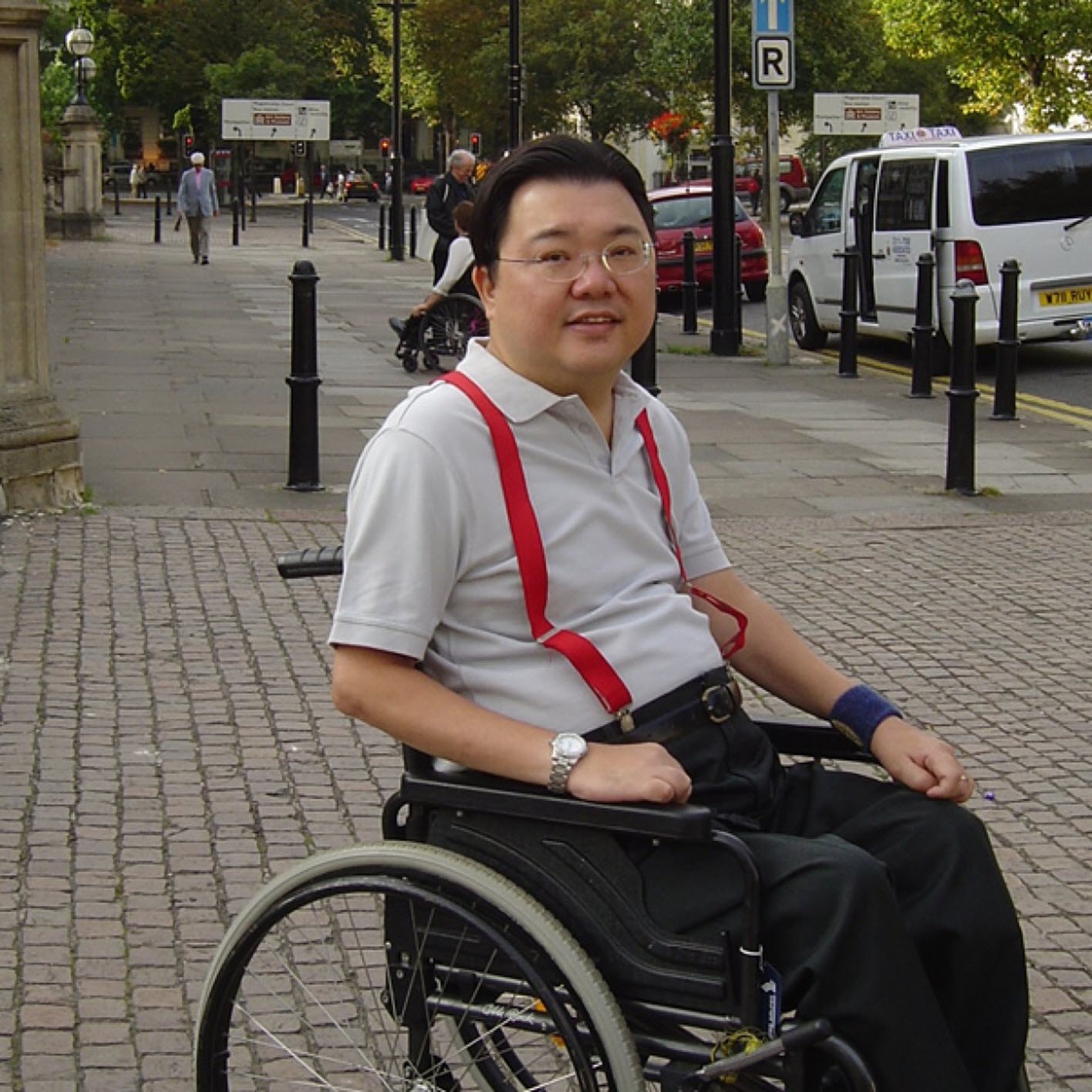 quadriplegic man sits in his wheelchair on a brick street