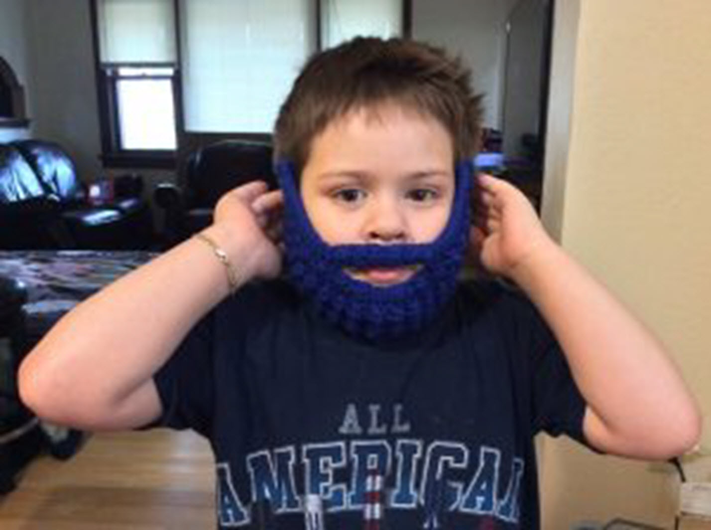 a young boy wears a crocheted beard