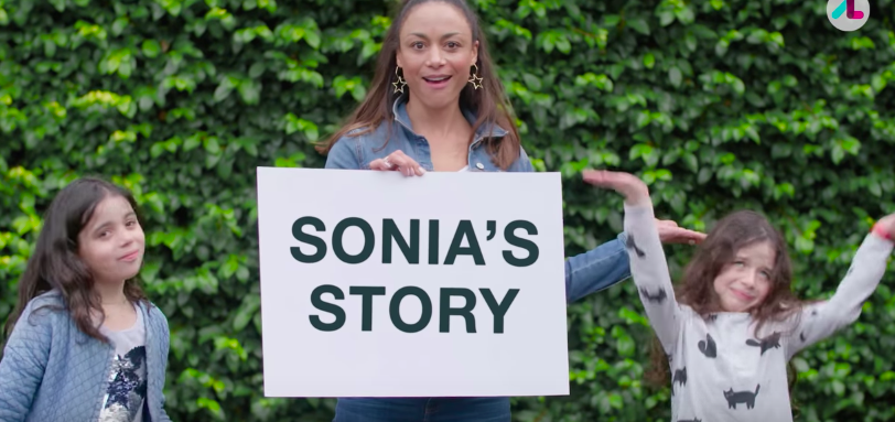 Sonia with her two daughters holding up a sign that says sonia's story