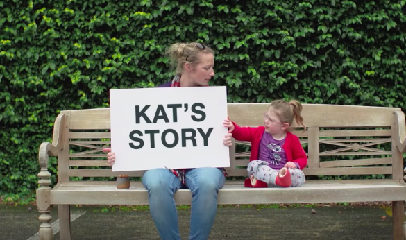 Kat with her daughter holding up a sign that says Kat's story