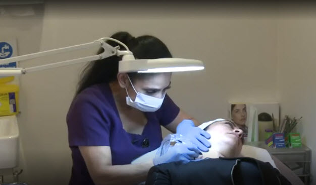 salon owner with transverse myelitis does a skin treatment on a client