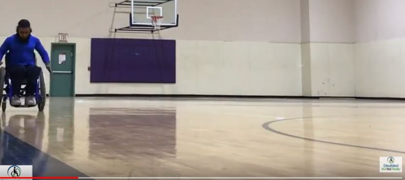 Wes pushing his wheelchair on a basketball court
