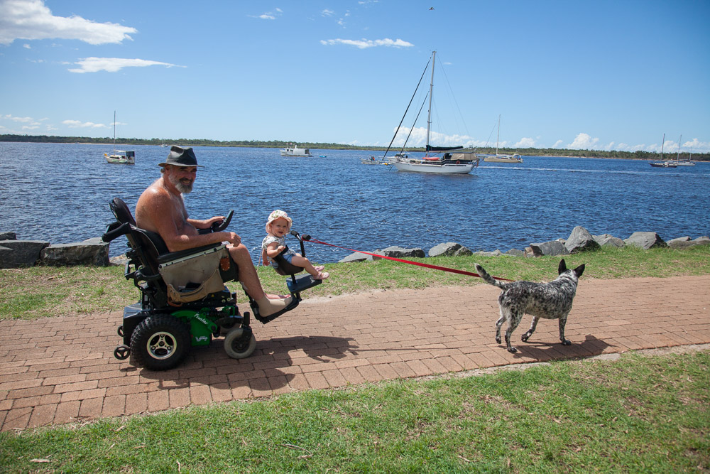 Paul with his daughter in her adaptation on his wheelchair, walking his dog by body of water