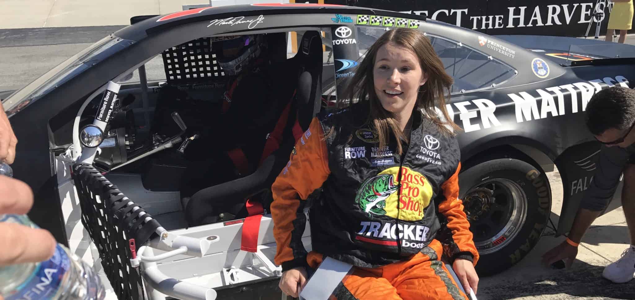 Picture of Kelly with an "Aw" expression in front of race car.