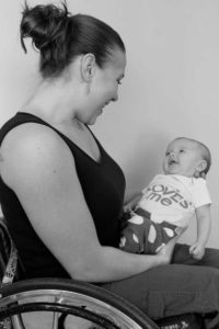 Black and white picture of Kristina holding her baby smiling down at her.