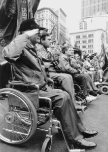 Men in wheelchairs lined up in the street in b&w