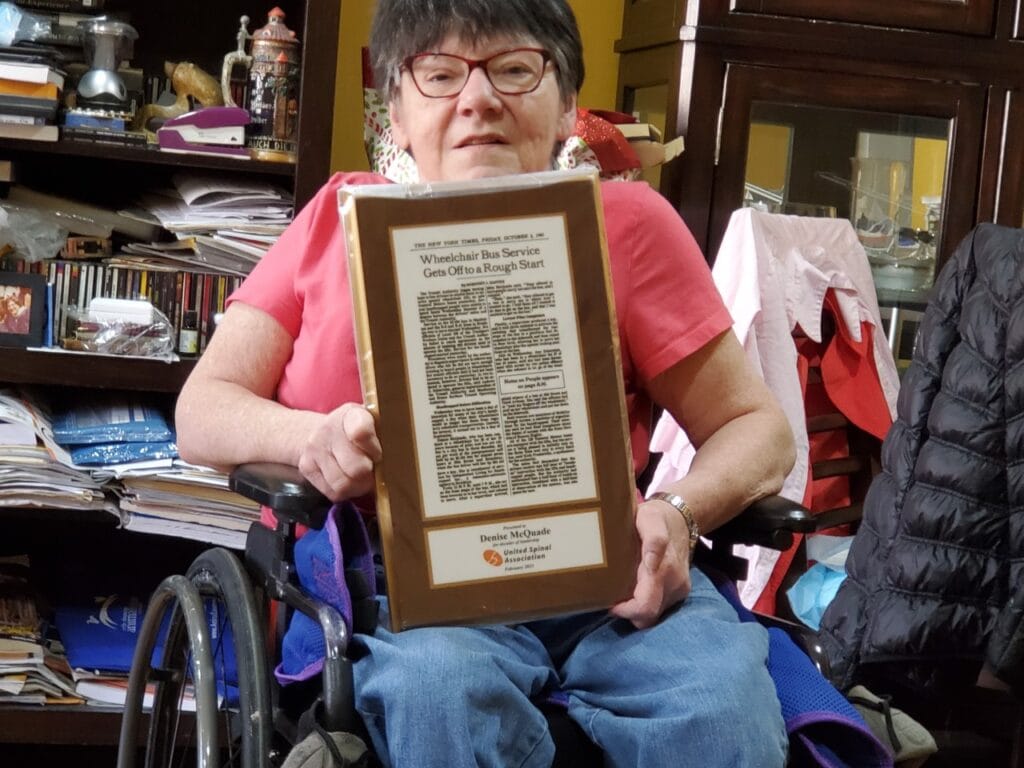 Denise holding plaque presented by United Spinal commemorating her advocacy on improving accessible transportation in NYC.