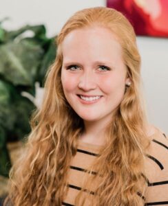 A smiling young woman with long red hair