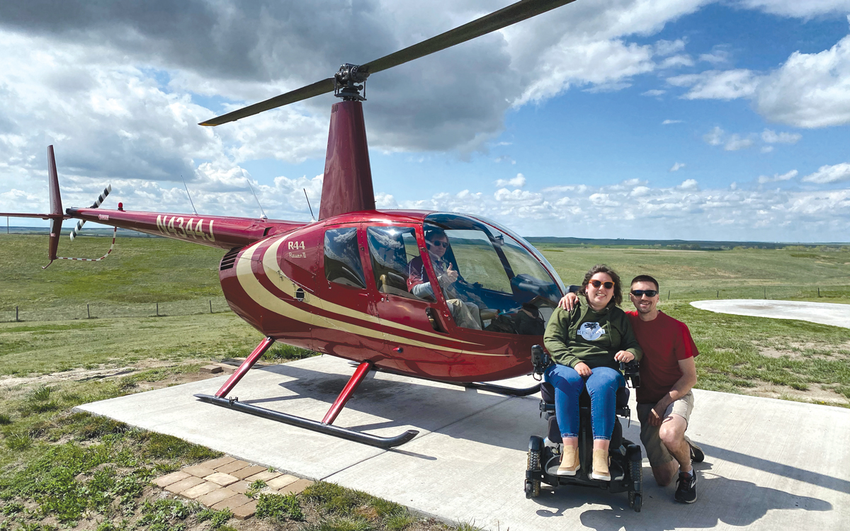 Michaela and husband in front of a helicopter.
