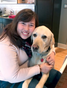 Michaela hugging her yellow lab service dog