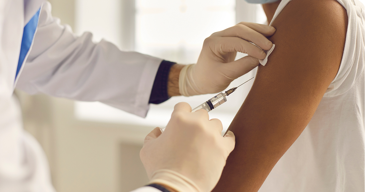 Closeup of doctor in medical gloves holding syringe and giving vaccine to patient
