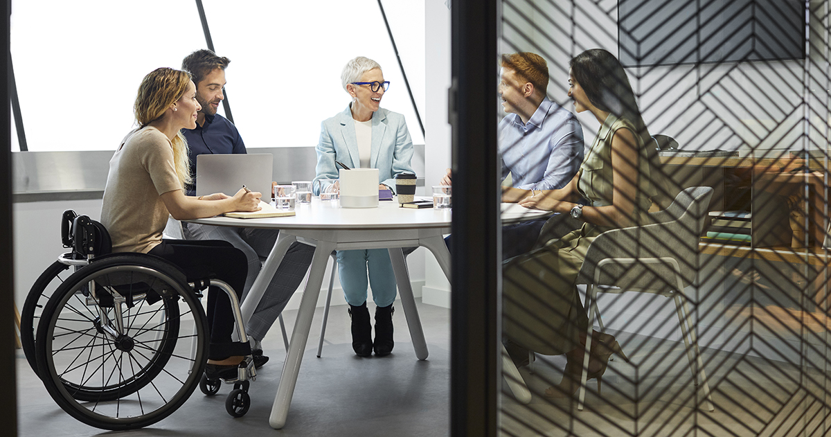 Male and female professionals discussing in board room. Disabled businesswoman communicating with coworkers in meeting. They are at office.