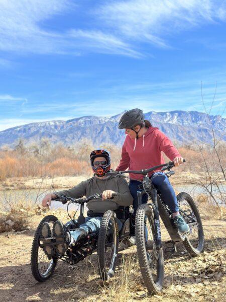 man and woman handcycling with mountains in background