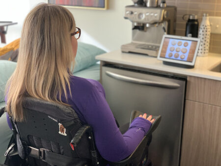 woman in wheelchair in kitchen looking at smart device