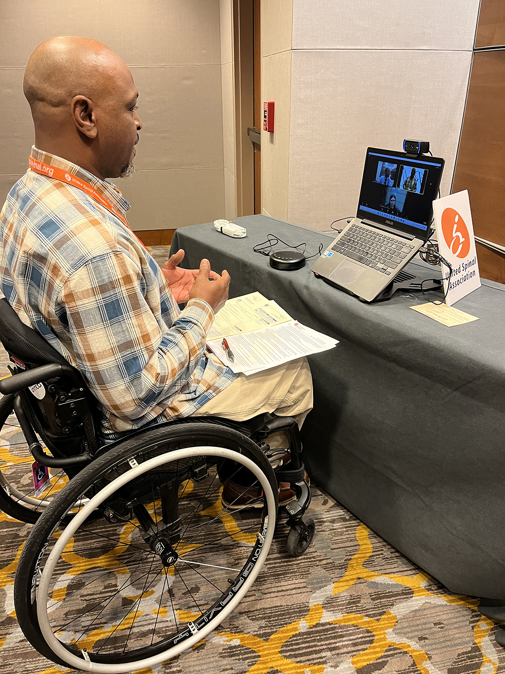man in wheelchair at table watching virtual ROCH session on laptop