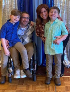 A wheelchair-using husband with his wife and two sons