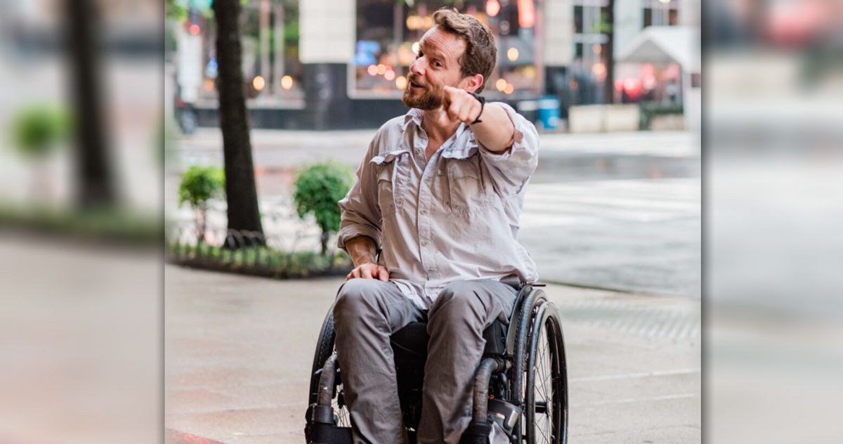 man in wheelchair pointing at camera