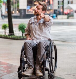 Male wheelchair user points at the camera