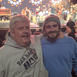 man with arm around son with a concert stage in the background