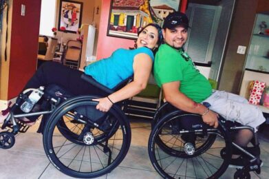 Two manual wheelchair uses sit back-to-back
