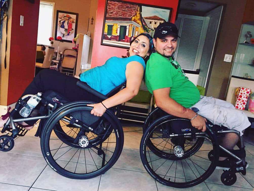 Two manual wheelchair uses sit back-to-back