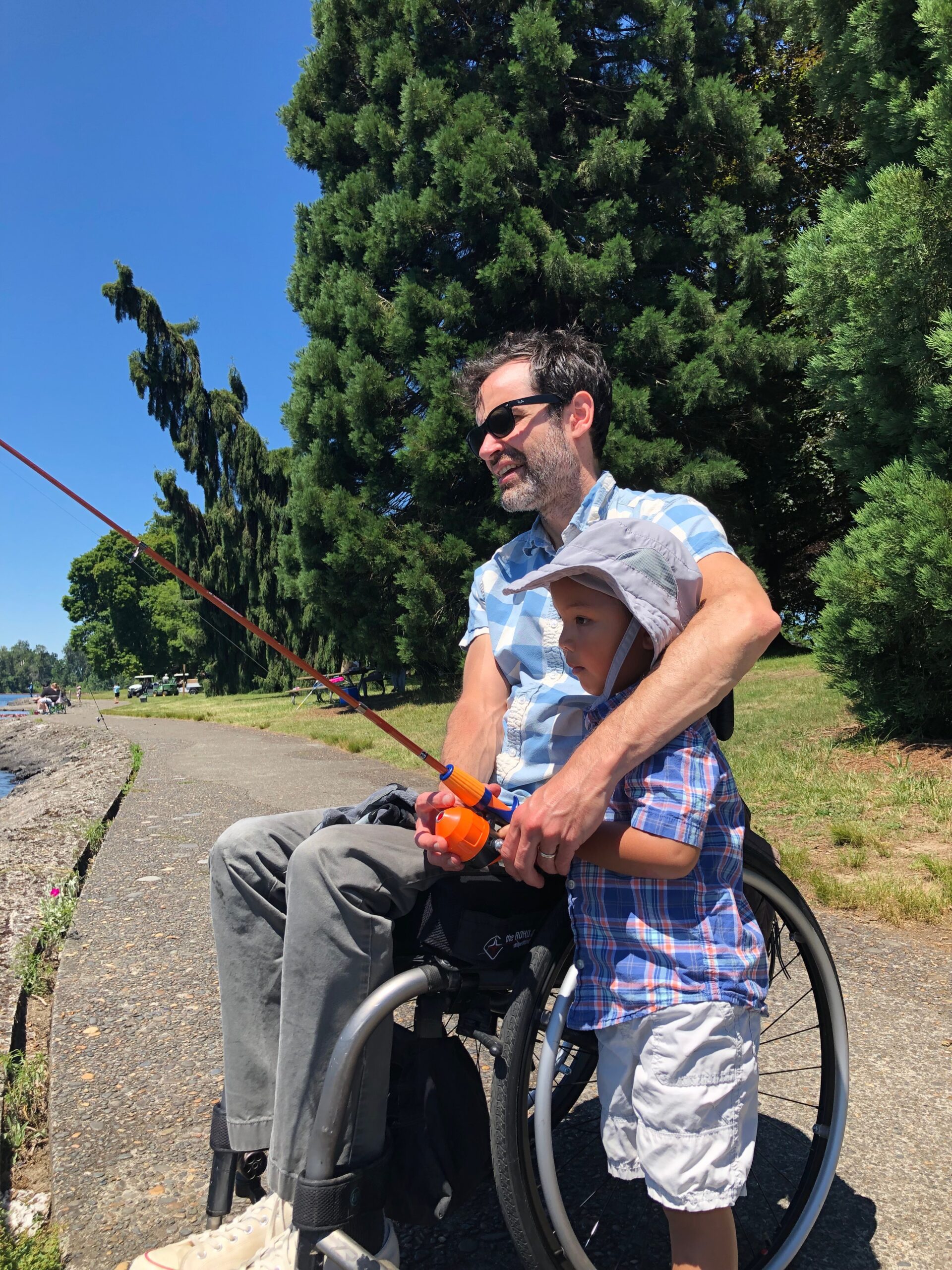 man in wheelchair fishing with young boy