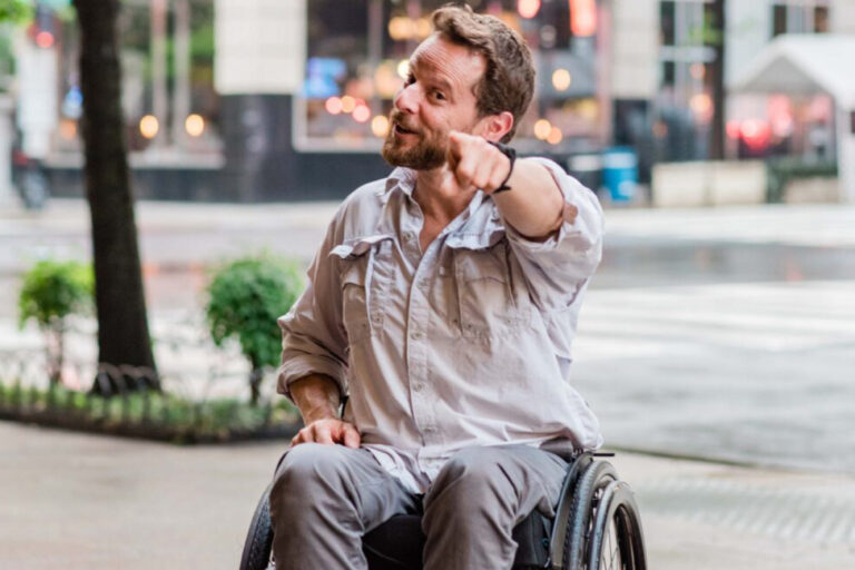 man in wheelchair pointing at camera