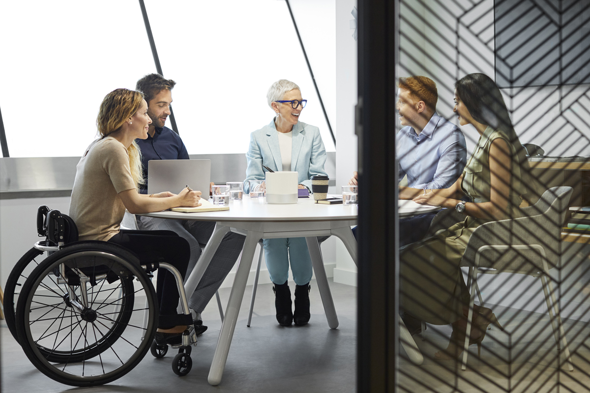 Male and female professionals discussing in board room. Disabled businesswoman communicating with coworkers in meeting. They are at office.