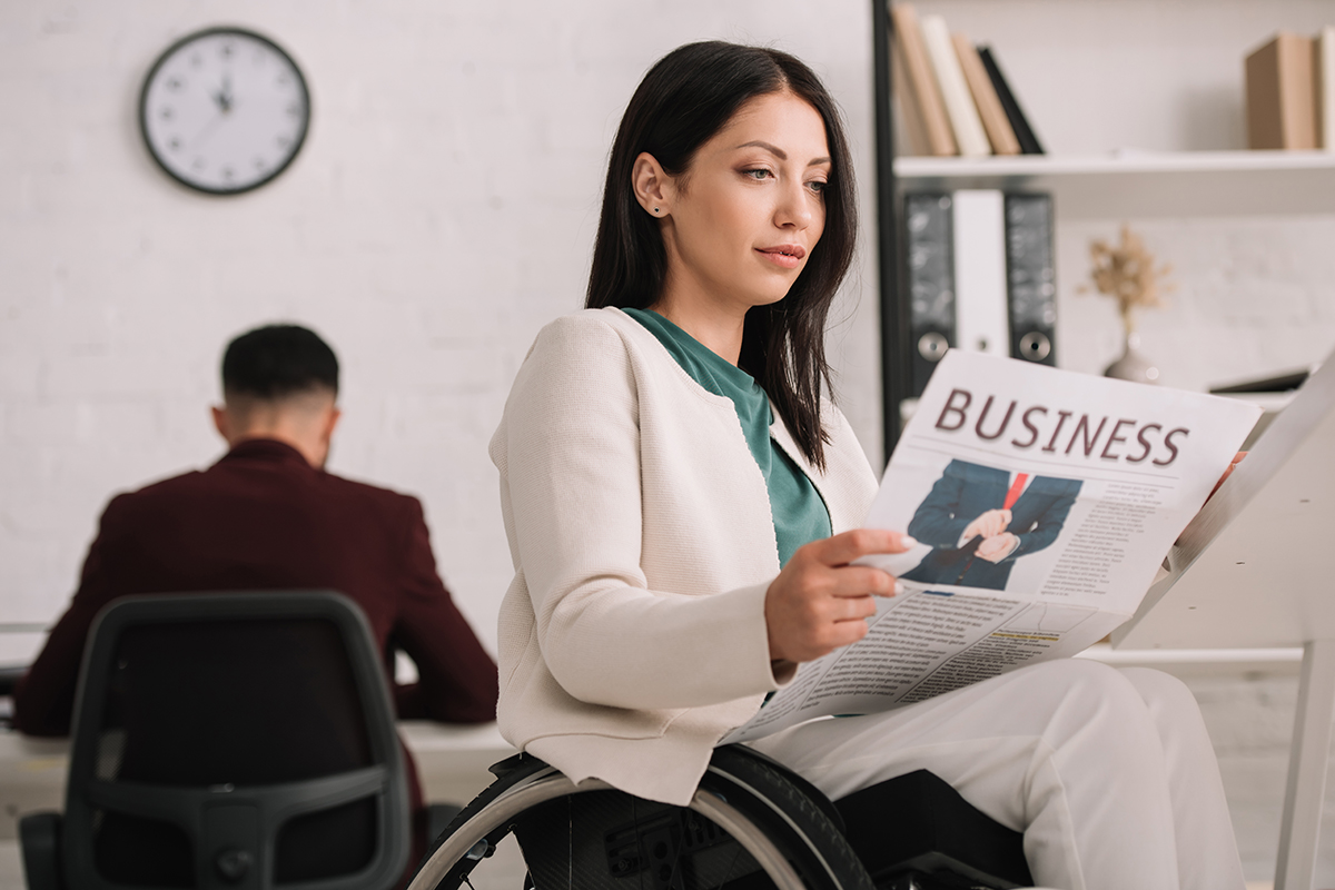 disabled businesswoman reading business newspaper in office