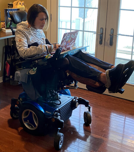 woman reclining in a powerchair working on laptop