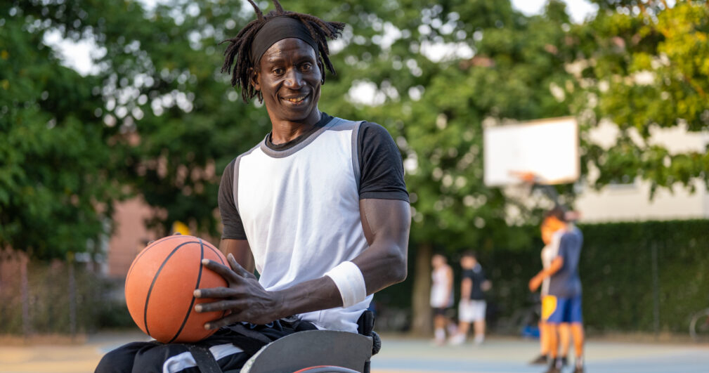 Afro American athlete on wheelchair playing basketball - sport disability concept
