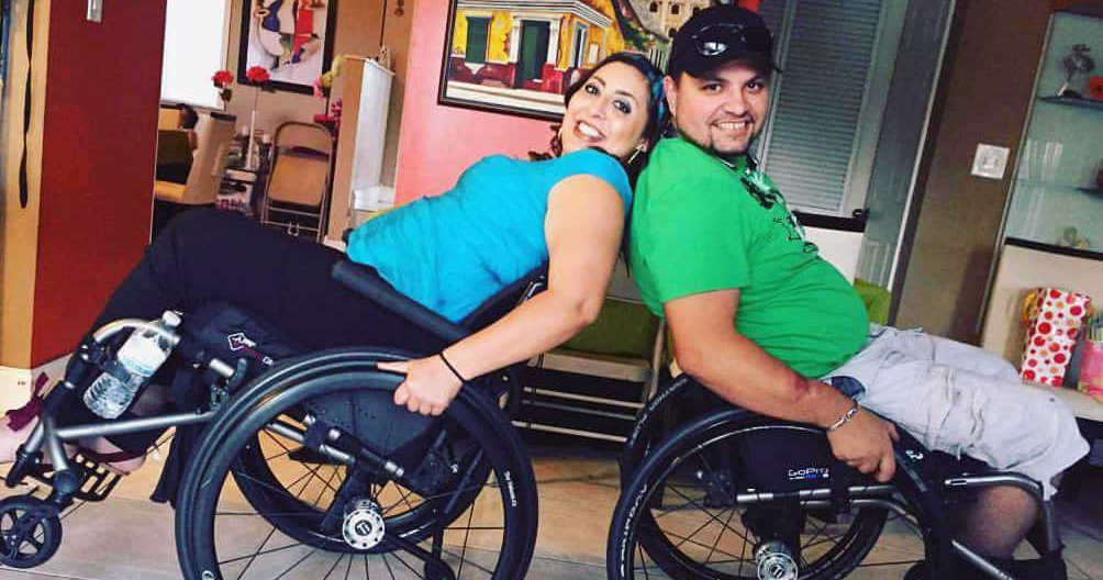 Two manual wheelchair uses sit back-to-back