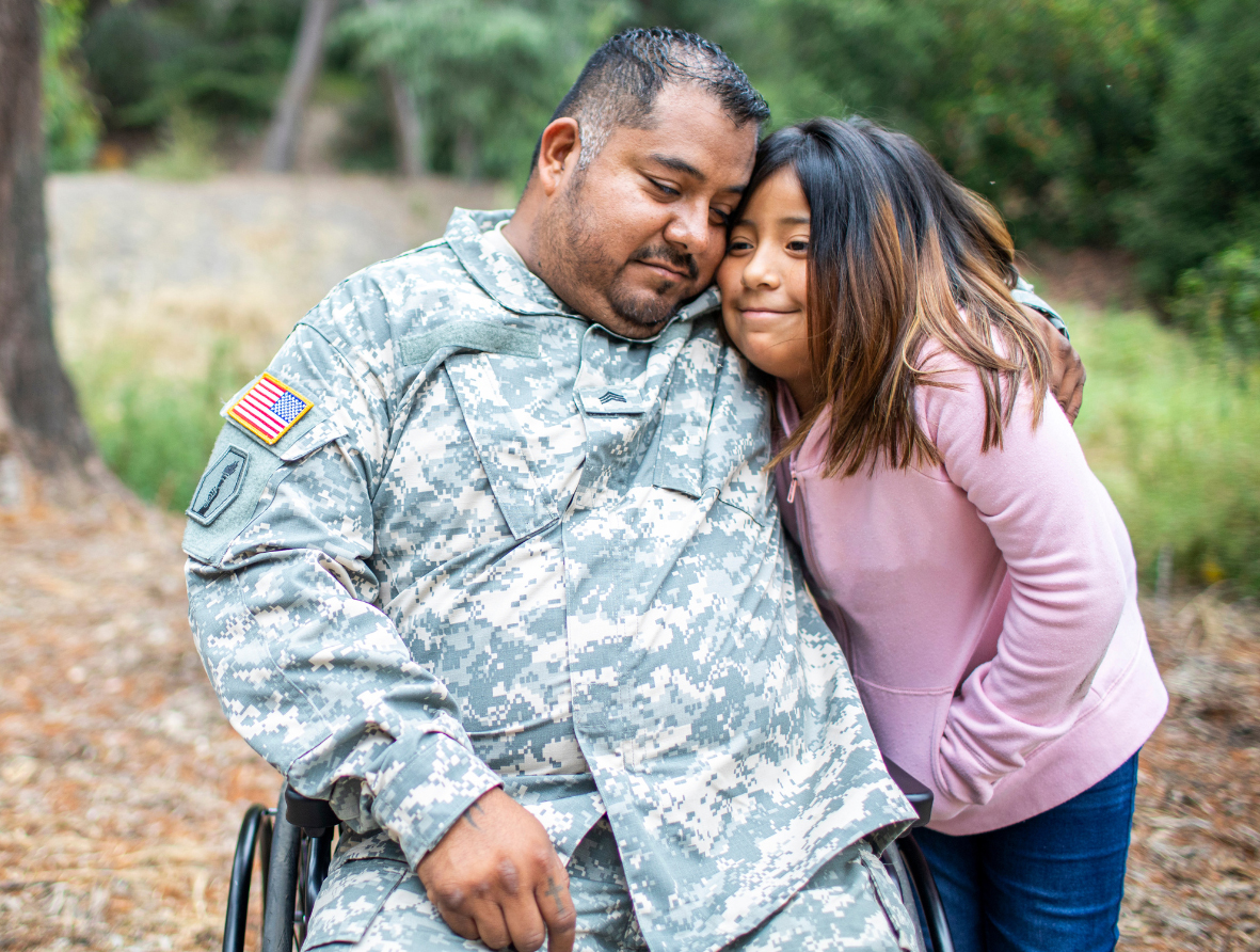 male veteran in wheelchair hugging young daughter