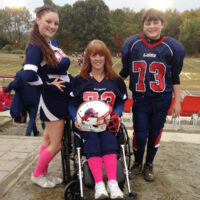 woman in wheelchair with children, one wearing football uniform the other a cheerleader