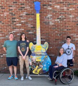 A family of four pose with an over-sized guitar at the Stax Museum of American Soul Music.