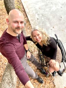 A fun selfie of a man standing next to a woman wheelchair user. 