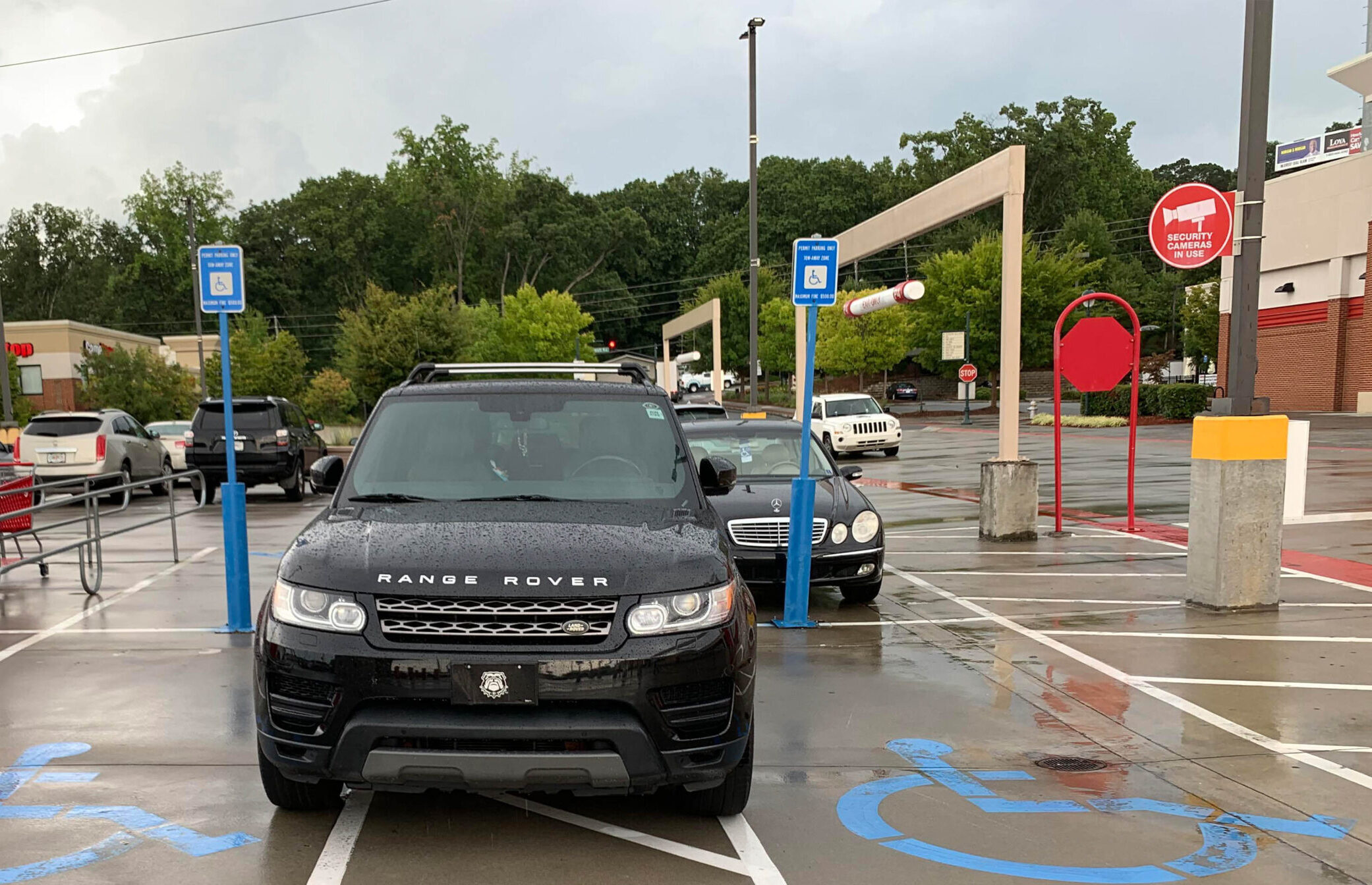 A Land Rover parked in the stripes between two accessible spaces, rending them both useless.