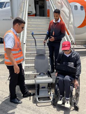 man in wheelchair preparing to transfer to airplane chair at foot of airplane stairs