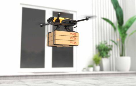 A drone flies to a house carrying pizzas.