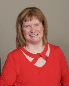 Leah Campbell is a blonde woman with bangs. She is wearing a red long sleeved shirt.